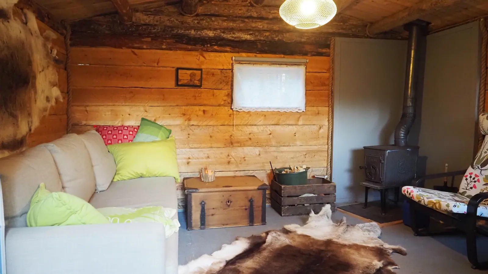 Inside the cabin: sofa, reindeer skin and wood stove