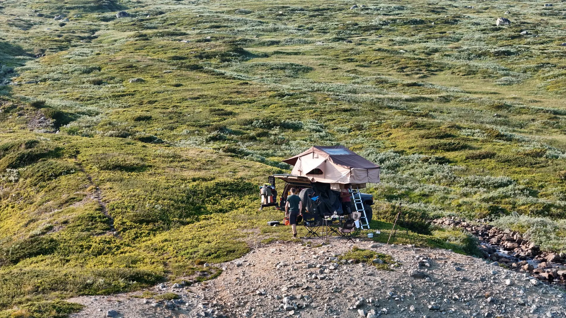 Rooftop tent camp on a wide green plateau, seen from above
