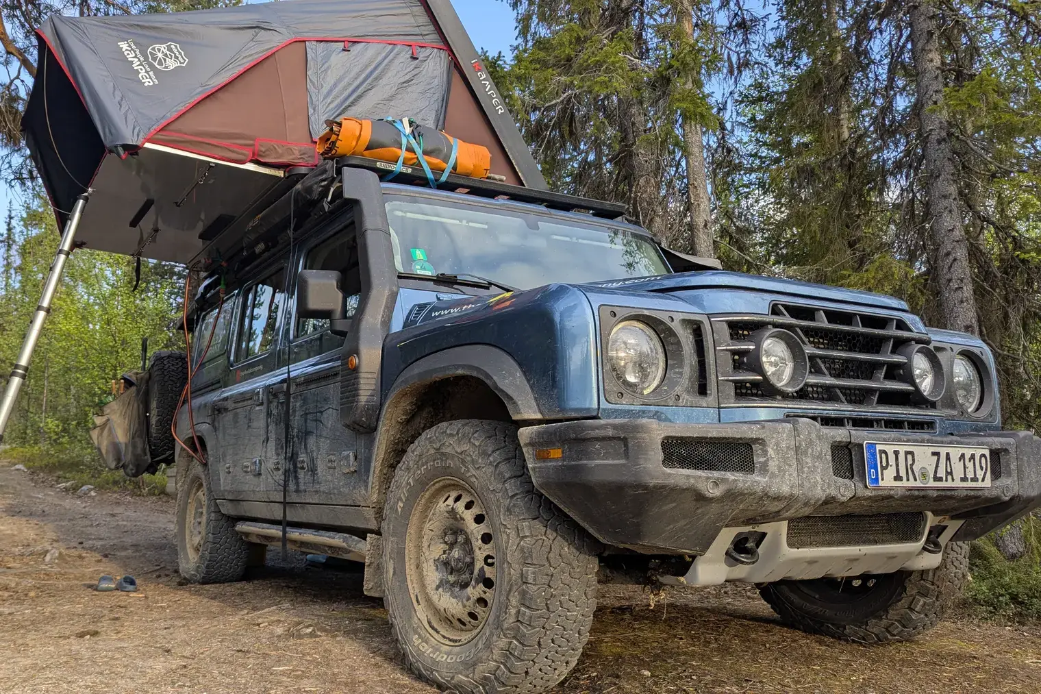 Ineos Grenadier with open rooftop tent in the forest