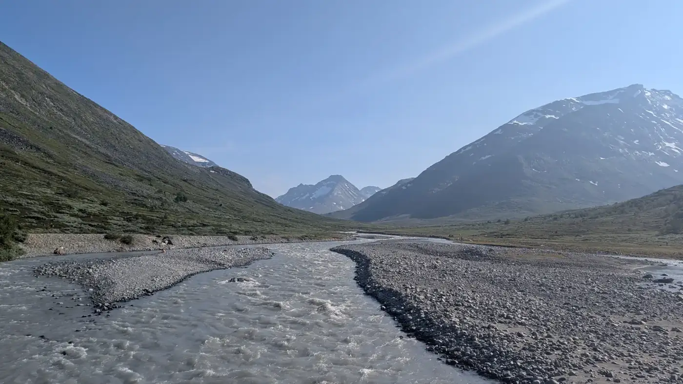 Wide river valley below snowy peaks