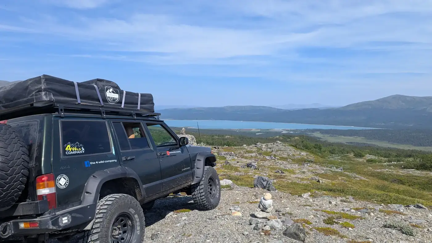 Jeep XJ with rooftop tent above a mountain lake in Norway