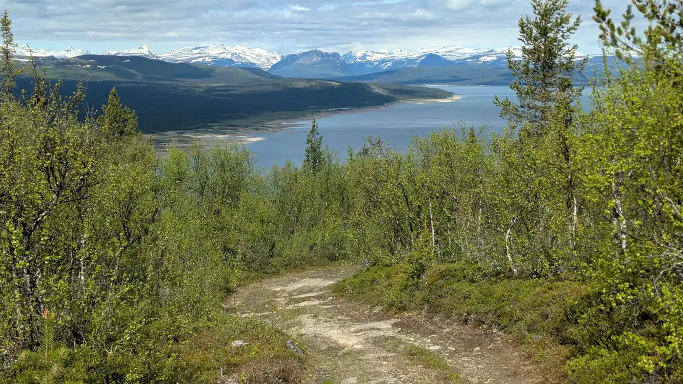 Gravel track above a lake with snowy mountains in Lapland