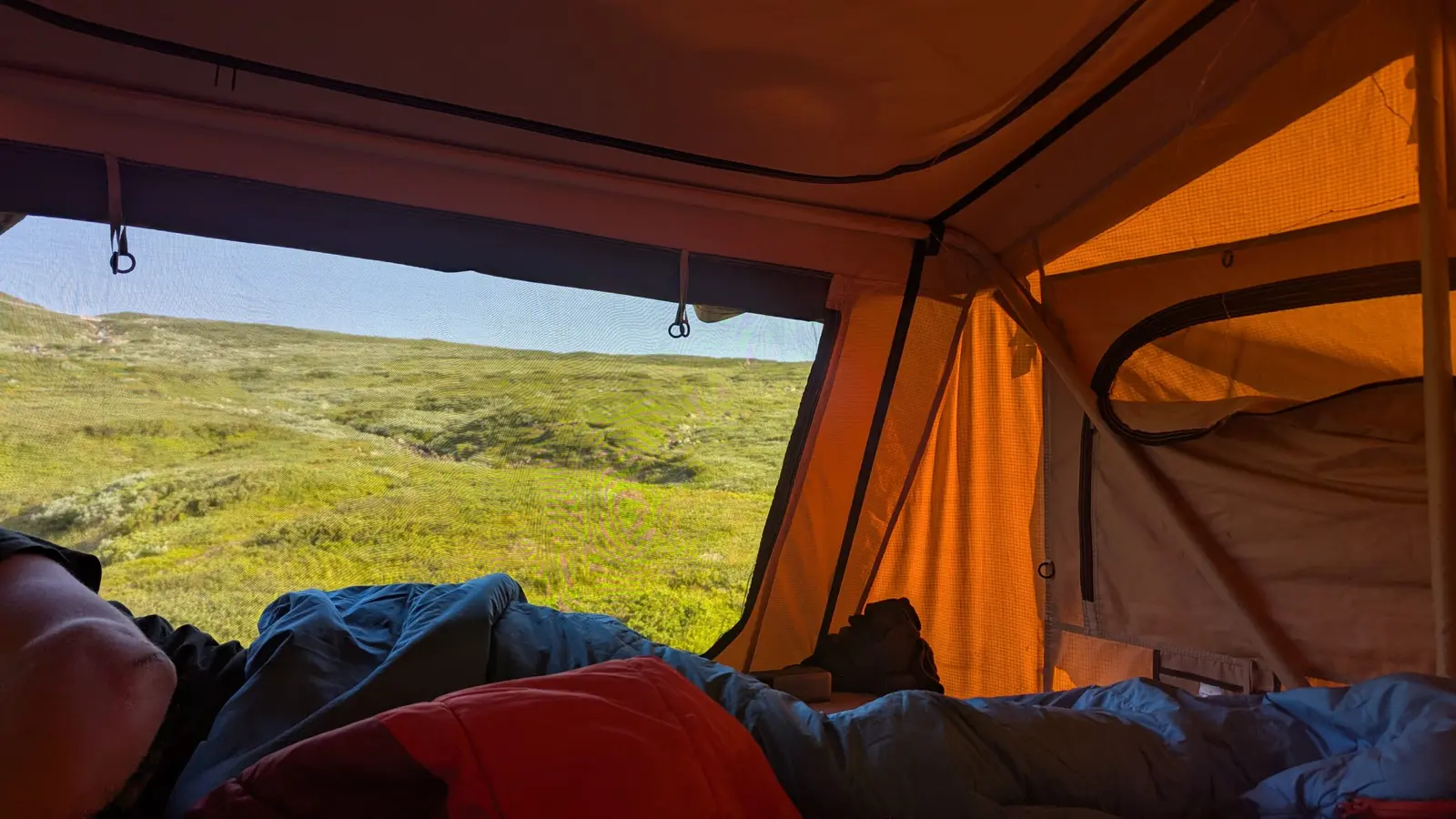 View from inside the rooftop tent over a mountain lake