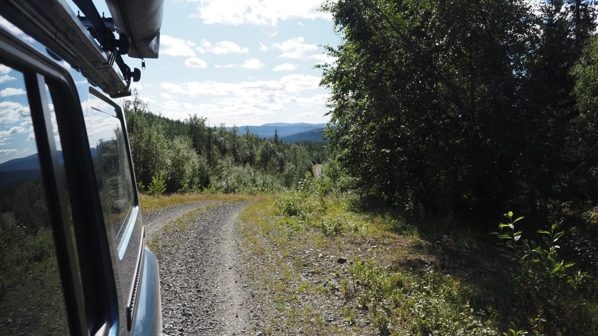 Grenadier 4x4 vehicle driving on a dirt road through the nature of Sweden